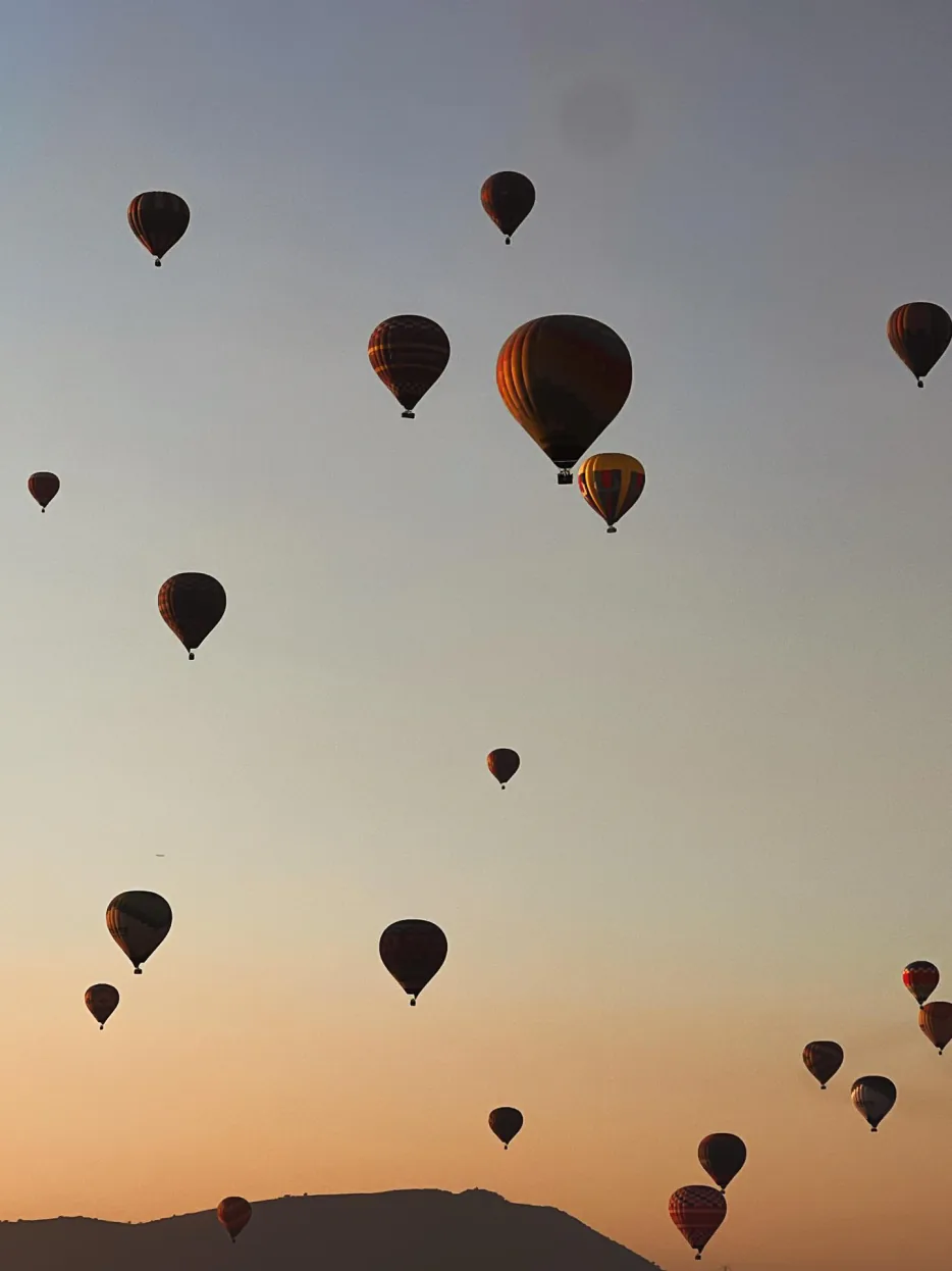 Siluetas de varios globos aerostáticos contra el amanecer sobre el valle de Teotihuacán