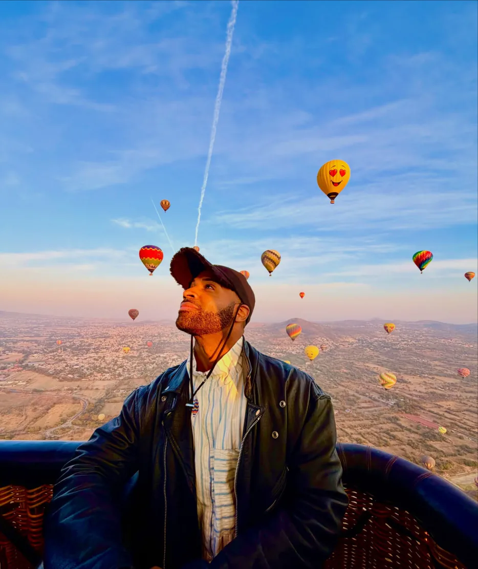 Pasajero asomado en la canasta mirando los demás globos aerostáticos en el cielo de Teotihuacán