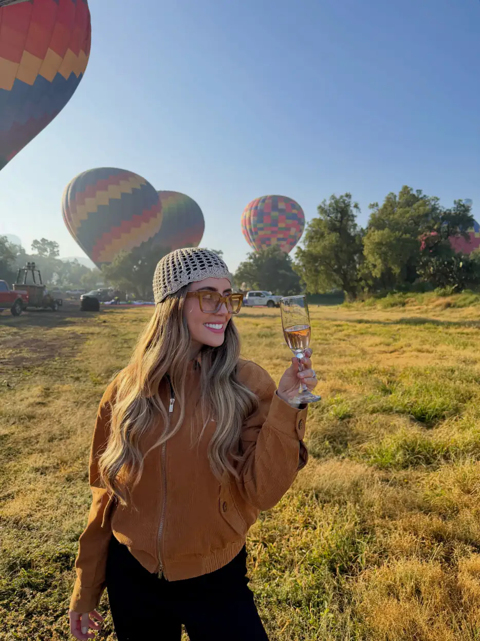 Mujer brindando con una copa de champán al terminar su vuelo en globo en Teotihuacán