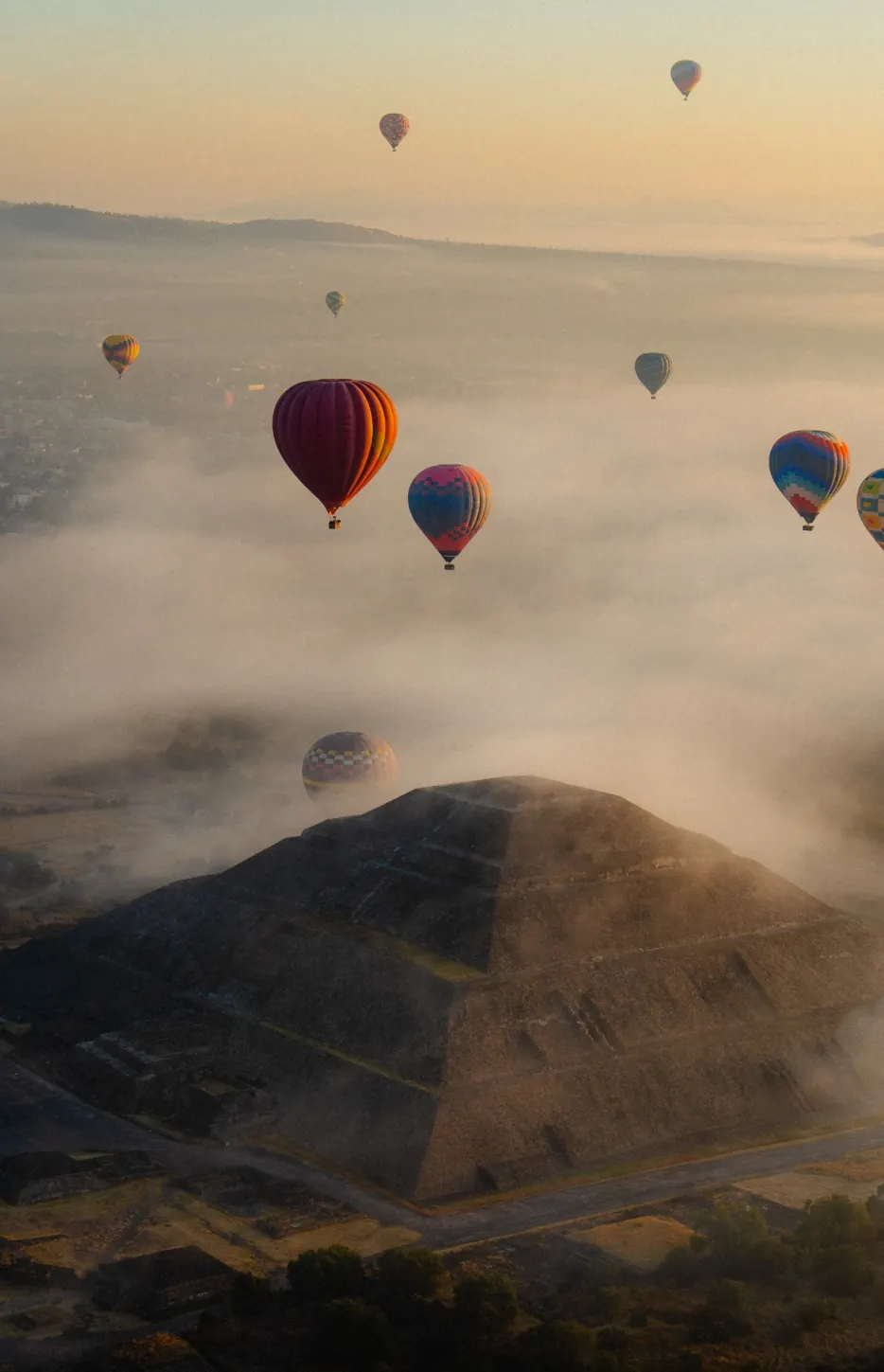 Pirámide del Sol de Teotihuacán entre la niebla con globos aerostáticos al amanecer